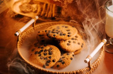 Sıcak bir sepetin içinde sıcak kurabiyeler, sıcak bir ortamda süt ve buhar.