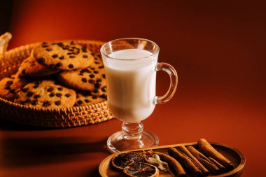 Baharatlı sıcak süt ve kurabiyeler akşam ışığında rahat bir masa ayarında.