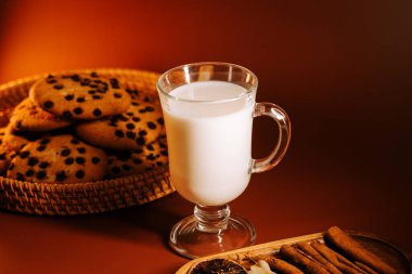 Sıcak arka planda bir bardak sütle lezzetli çikolatalı kurabiyeler.