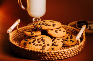 Sıcak, davetkar bir yüzey üzerinde bir bardak sütle sıcak bir ortamda taze pişmiş kurabiyeler.