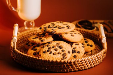 Sıcak bir masada dokuma sepetinde servis edilen taze pişmiş çikolatalı kurabiyeler.