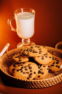 Sıcak kurabiyeler dokuma sepetinde bir bardak sütle servis edilir.