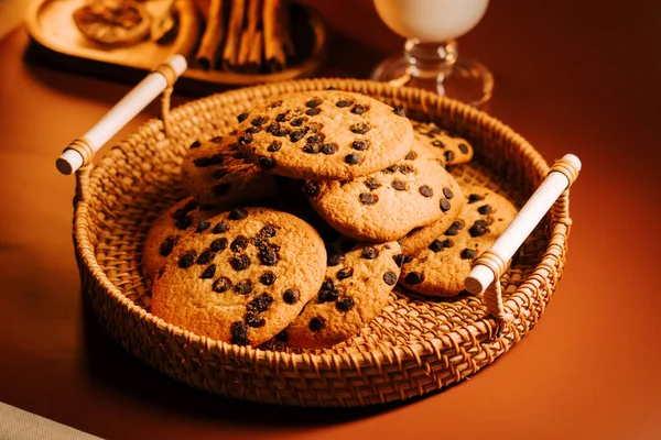 Sıcak bir masanın üstünde dokuma sepetinde taze pişmiş çikolatalı kurabiyeler.
