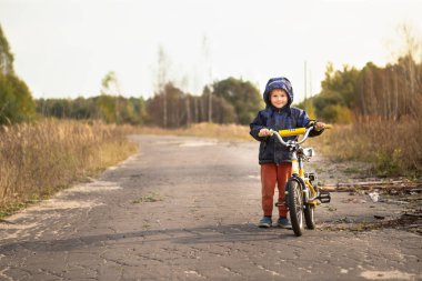 Çocuk sonbahar aylarında bisiklete binmek öğrenme. Sıcak renkler. 