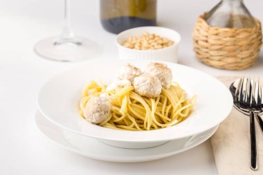 Spagetti kremsi tavuk köfte ile çam fıstığı ve beyaz şarap ile beyaz tabakta servis