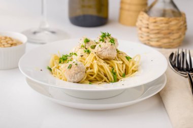 Spagetti çam fıstığı ile beyaz tabakta kremsi tavuk köfte ile