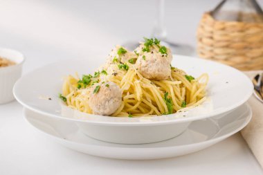 Spagetti çam fıstığı ile beyaz tabakta kremsi tavuk köfte ile