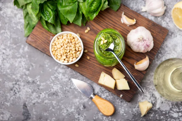 Pesto sauce in a bottle with ingredients (fresh basil, cheese, pine nuts, garlic)