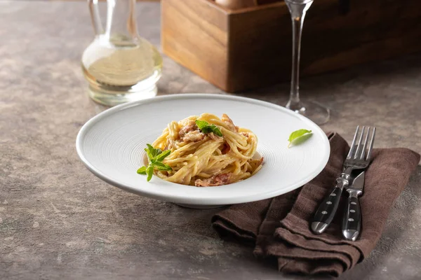 Koyu beyaz tabakta kekikli makarna.