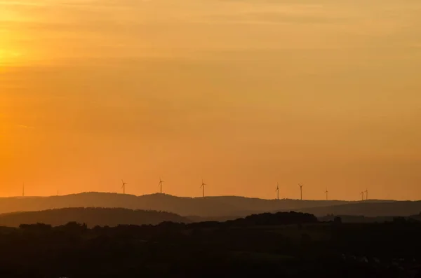 Günbatımı üzerinde Gladenbacher windpark. Rüzgar jeneratörleri günbatımı arka plan üzerinde siluetleri. Manzara.