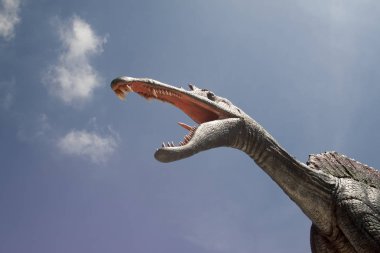 Heykel dinozor mavi gökyüzünün altında ağzını açar.