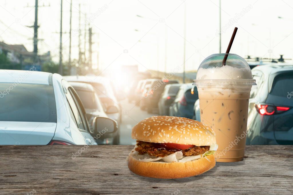 Coffee and hamburger on wood floor with blurred of transportation on the road.