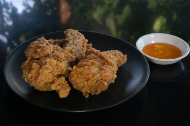 Kahverengi bir tabakta soslu iki kızarmış tavuk..