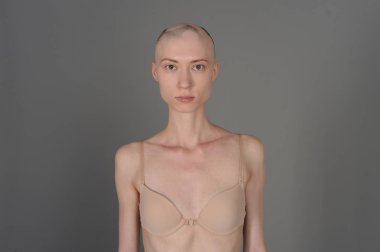 gri arka plan üzerinde poz bej iç çamaşırı kel kız