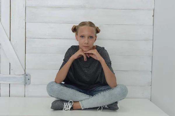 Fille dans une veste grise et un jean bleu dans le studio sur un fond gris — Photo