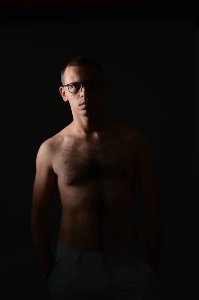 Un homme montre son torse et pose dans le Studio sur un fond noir — Photo