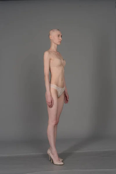 Calvo ragazza in lingerie beige posa su sfondo grigio — Foto Stock