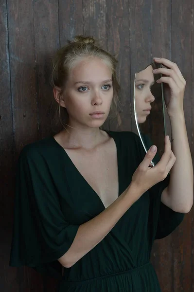 Fille dans une robe verte avec un décolleté plongeant posant avec un éclat de verre dans le studio sur fond en bois — Photo