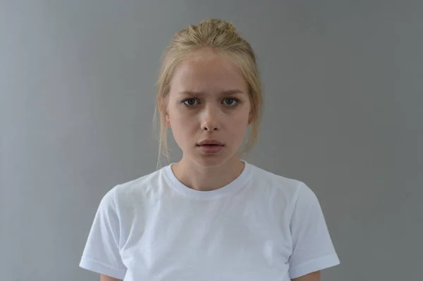 Fille en t-shirt blanc montre les émotions dans Studio sur fond gris — Photo