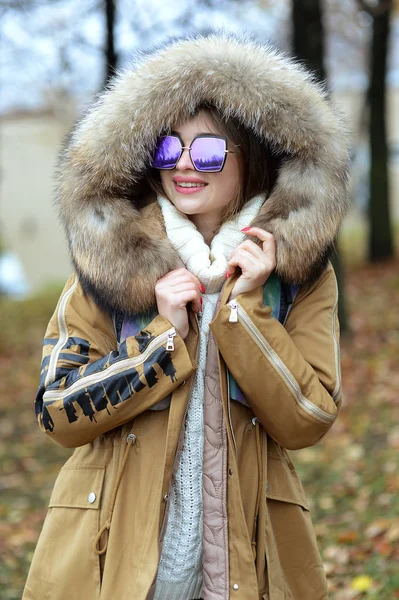 Dziewczyna w dół kurtki z futrem i niebieski okulary spaceru w lesie — Zdjęcie stockowe