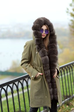 Yeşil ceketli güzel Kız bardaklarda göl kenarında poz kürk yakalı