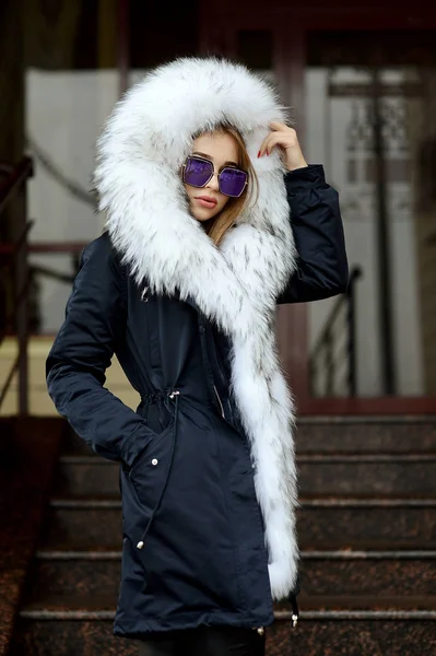 bir kız bir beyaz kürk yaka ve sokakta poz gözlük ile siyah ceketli