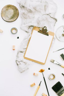 Düz yatıyordu, en iyi görünümü sanatçı ev ofis çalışma alanı Resepsiyon Pano mockup, boya fırçaları, battaniye ve beyaz arka plan üzerinde araçları.