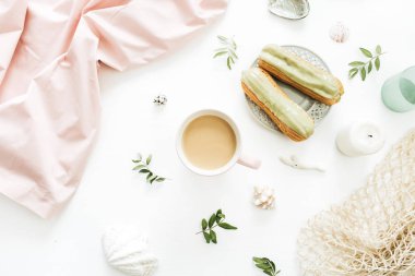 Kahve kupa, fıstıklı kek, yaprak, beyaz arka plan üzerinde soluk pembe battaniye ve deniz kabukları ile kahvaltı kavramı. Düz yatıyordu, en iyi görünüm kompozisyon tarz.