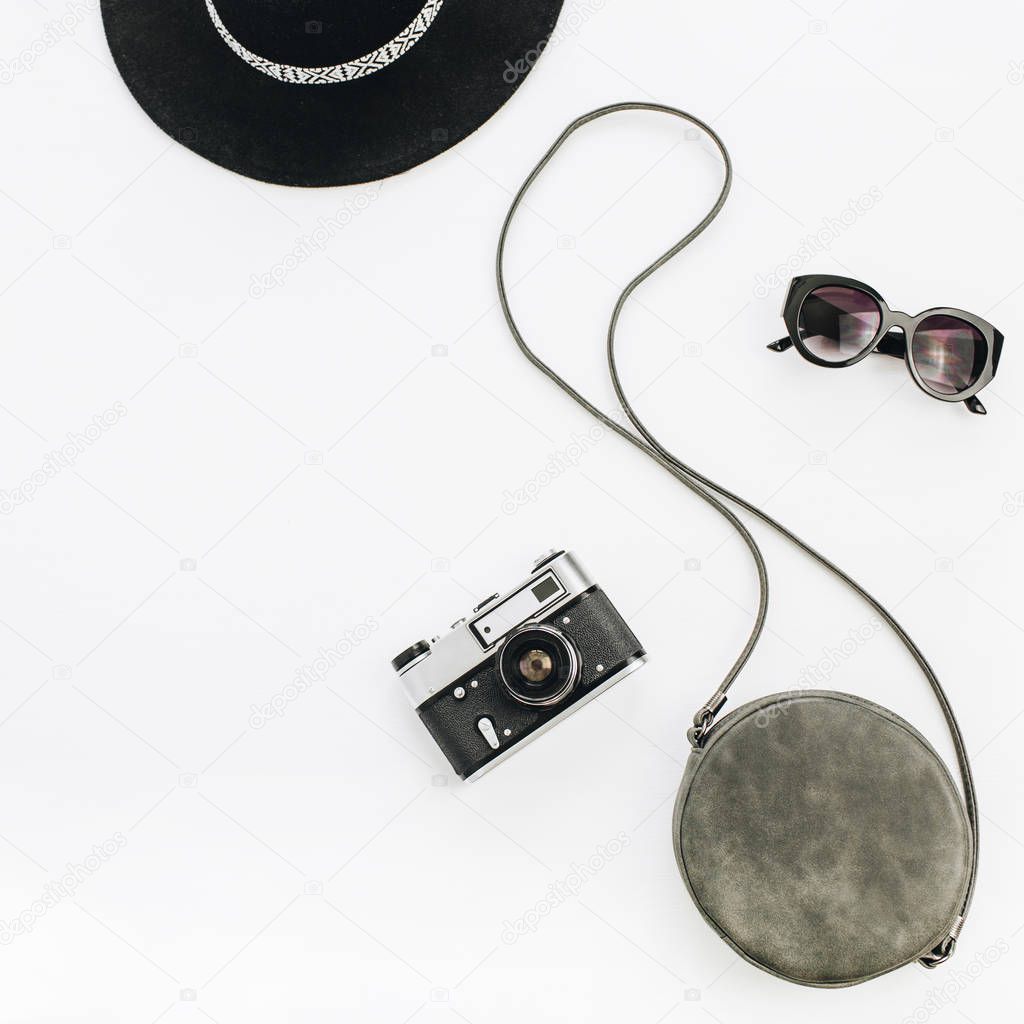 Black stylish female accessories: sunglasses, hat, purse and retro camera. Flat lay, top view minimal summer fashion concept.