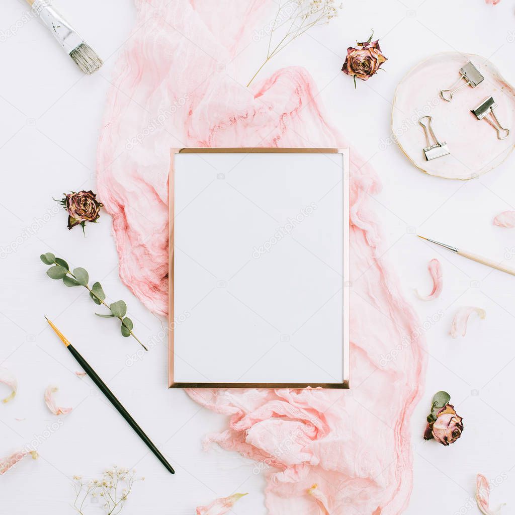 Creative festive composition with photo frame mock up, pink blanket, flowers, eucalyptus branches and brushes on white background. Flat lay, top view stylish template.