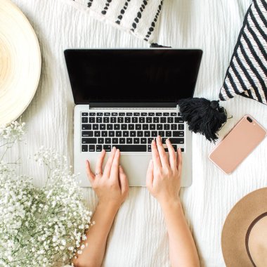 Yatakta dizüstü bilgisayarda çalışan genç kadın. Yaşam tarzı kompozisyon yukarıdan manzaralı. Serbest meslek ya da moda blogger ev çalışma alanı kavramı. Düz yatıyordu, en iyi görünümü.