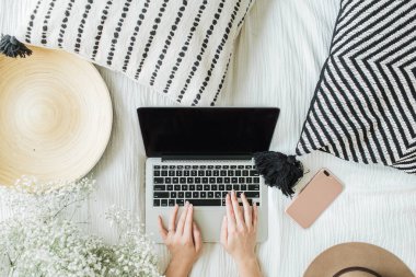 Genç kadın yatakta dizüstü bilgisayarda yazarak. Yaşam tarzı kompozisyon. Düz yatıyordu, en iyi görünüm. Serbest meslek ya da moda blogger ev çalışma alanı kavramı.