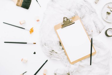 Düz yatıyordu, en iyi görünümü sanatçı ev ofis çalışma alanı Resepsiyon Pano mockup, boya fırçaları, battaniye ve beyaz arka plan üzerinde araçları.