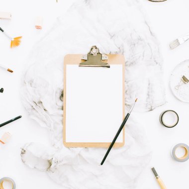 Düz yatıyordu, en iyi görünümü sanatçı ev ofis çalışma alanı Resepsiyon Pano mockup, boya fırçaları, battaniye ve beyaz arka plan üzerinde araçları.