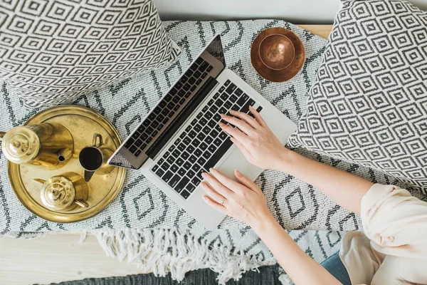 Young woman typing on laptop in bed. Lifestyle hero header with view from above. Freelancer or fashion blogger home workspace concept.