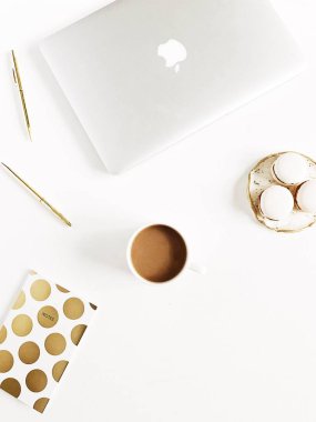 Modern altın ev ofis büro dizüstü, beyaz arka plan üzerinde kupa kahve macaroons, kalem ile stilize. Düz yatıyordu, en iyi görünümü yaşam tarzı kavramı.