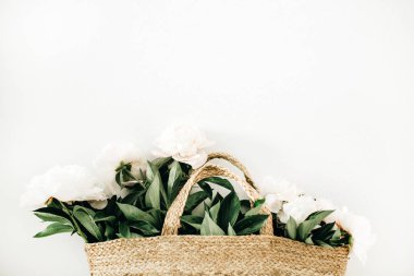 Hasır çanta beyaz arka plan üzerinde beyaz şakayık çiçekleri ile. Düz yatıyordu, en iyi görünümü yaz çiçek kavramı.