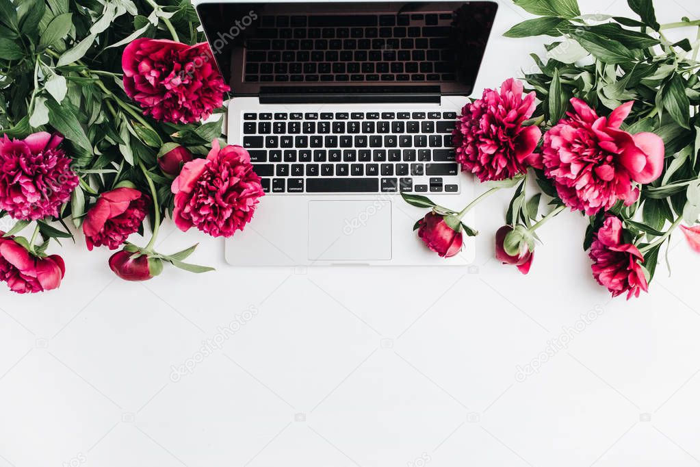 Laptop and pink peonies flowers on white background. Flat lay, top view mock up.