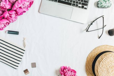 Düz yatıyordu, en iyi görünüm çerçevesinde kadın office Resepsiyon workspace laptop, pembe peony çiçek buketi, kozmetik, Gözlük, beyaz arka plan üzerinde hasır şapka ile. Moda ya da güzellik blog kahraman üstbilgi şablonu.