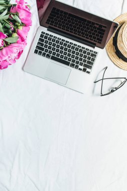 Düz yatıyordu, en iyi kadın ofis resepsiyon çalışma alanı görüntüle laptop, pembe peony çiçek buketi, Gözlük, beyaz arka plan üzerinde hasır şapka ile. Moda blog kadar sahte.