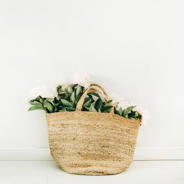 Hasır çanta beyaz arka plan üzerinde beyaz şakayık çiçekleri ile. Yaz çiçek kavramı.