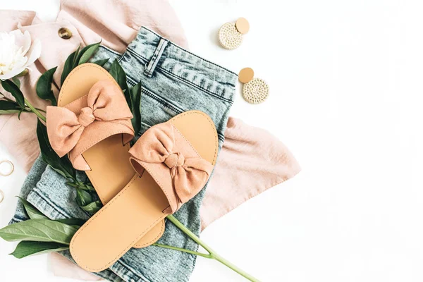 Female fashion background with white peony flower, slippers, sunglasses, earrings, shorts, t-shirt. Flat lay, top view.