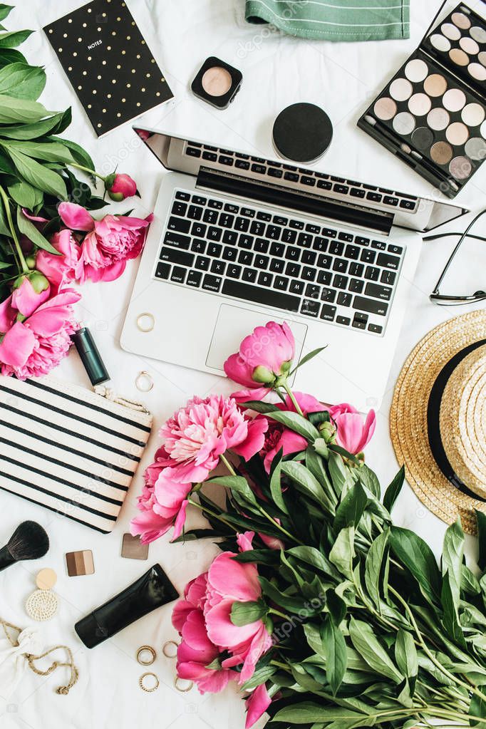 Flat lay fashion feminine office desk with laptop, pink peony flowers, cosmetics, accessories. Top view fashion or beauty blog summer floral background.