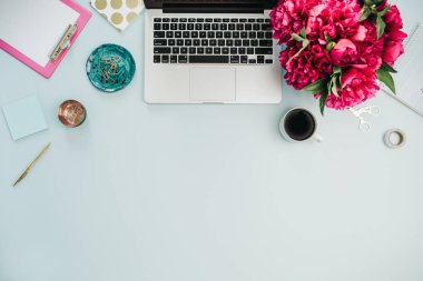 Çalışma alanı dizüstü ve pembe şakayık ile mavi arka plan üzerinde buket çiçekler. Düz yatıyordu, en iyi görünüm ev ofis masası.