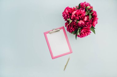 Minimalist düz ofis tablo masası Pano, pembe peony çiçek buketi mavi zemin üzerine yatırın. Üstten görünüm iş kavramı kadar sahte.