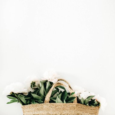 Hasır çanta beyaz arka plan üzerinde beyaz şakayık çiçekleri ile. Düz yatıyordu, en iyi görünümü yaz çiçek kavramı.