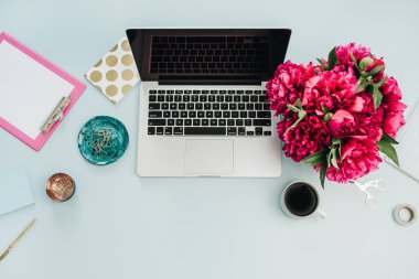 Düz yatıyordu, en iyi kadın ev ofis resepsiyon çalışma alanını göster mavi zemin üzerine. Dizüstü bilgisayar, pembe peonies çiçek buketi, kahve, pano ve aksesuarları. Blog ya da sosyal medya kahraman üstbilgi şablonu.