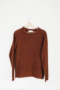 Beyaz arka plan üzerinde izole askı üzerinde kahverengi kazak. Sonbahar moda en az kavramı.