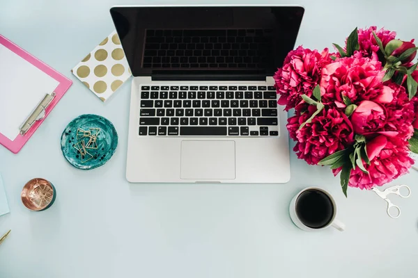 工作区与膝上型电脑和粉红色的牡丹花花束在蓝色背景 顶部查看家庭办公办公桌 — 图库照片