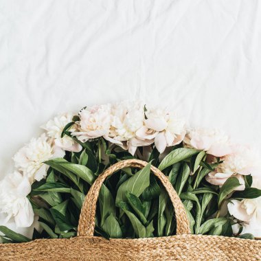 Hasır çanta beyaz arka plan üzerinde beyaz şakayık çiçekleri ile. Düz yatıyordu, en iyi görünümü yaz çiçek kavramı.